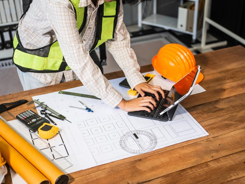 Female architect engineer drafting blueprints using CAD software, focusing sustainable
